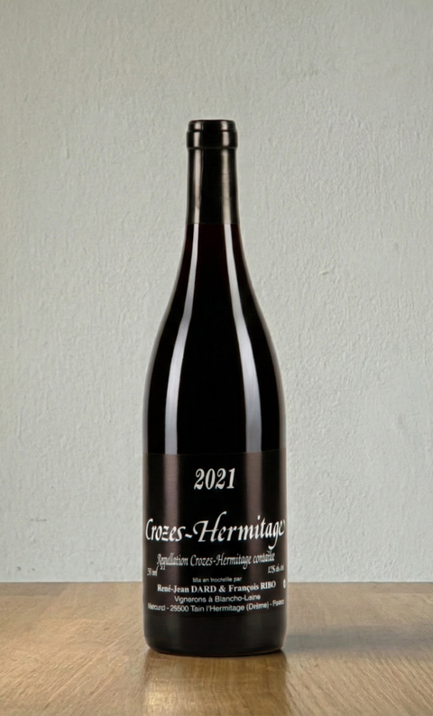 Wine bottle labeled '2021 Crozes-Hermitage' on a wooden surface with a white background